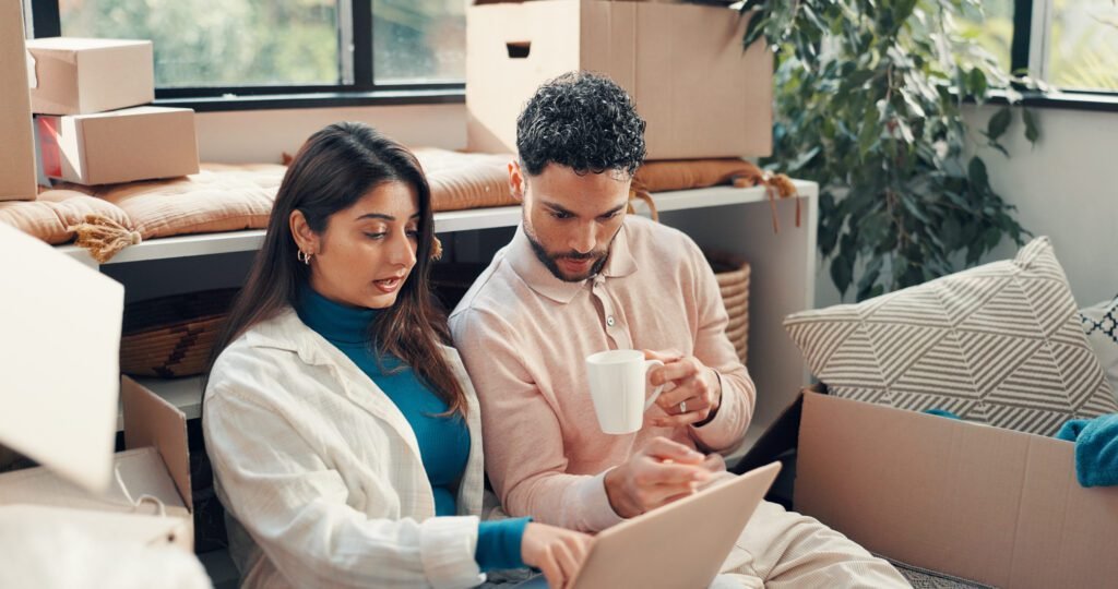 laptop boxes couple new home planning mortgage property investment deal computer reading man with woman real estate research with information by cardboard house together - DSM PROPERTIES